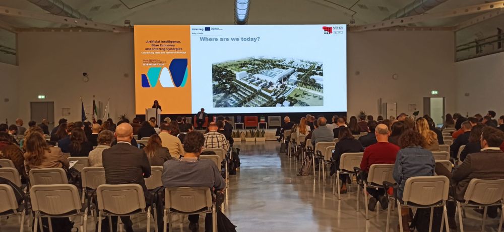 La cooperazione Interreg sostiene la Blue Economy creando connessioni concrete tra idee e territori. L'immagine ritrae i partecipanti al convegno ripresi di spalle mentre ascoltano i relatori e guardano lo schermo con le immagini